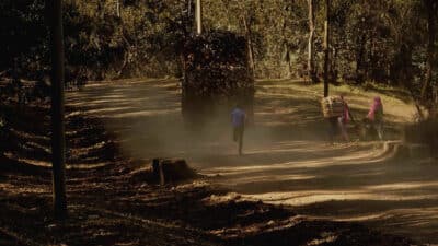 People walking behind a wood truck on a dusty road