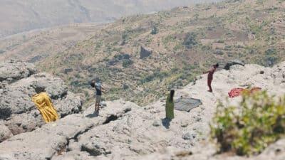 From a distance, three people standing on cliffs facing the sky