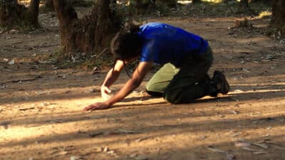 Person on the floor making shapes in the dirt